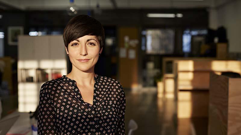 Confident woman standing in a modern office with warm sunlight